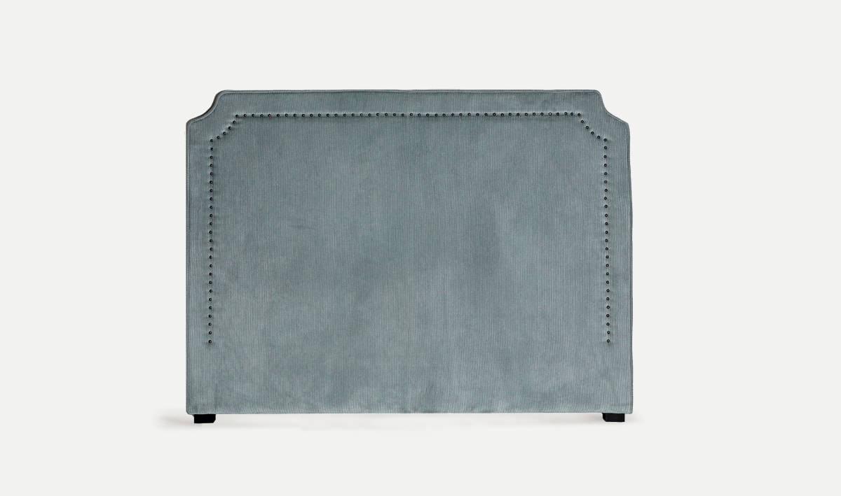 The Dorian headboard features soft blue corduroy upholstery and refined nailhead trim, adding timeless elegance to the bedroom.